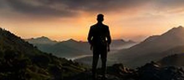 Founder berjas berdiri di lereng gunung saat matahari terbenam